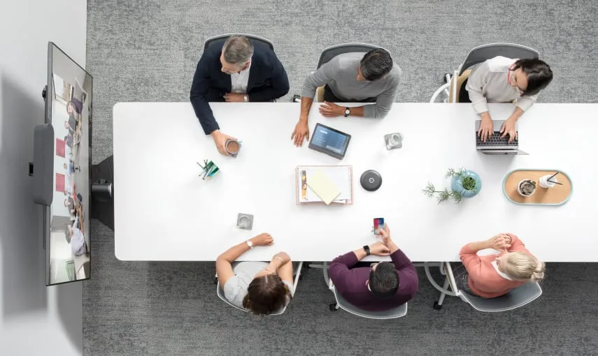 Overhead view of a boardroom table during a hybrid meeting